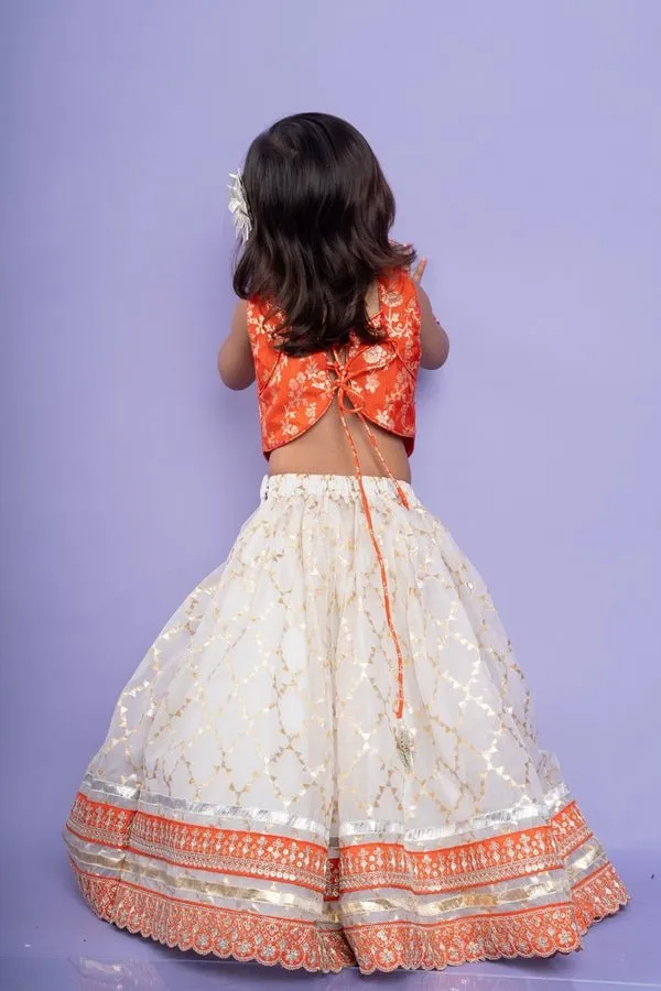 Festive orange brocade top with a golden-patterned white lehenga, perfect for celebrations