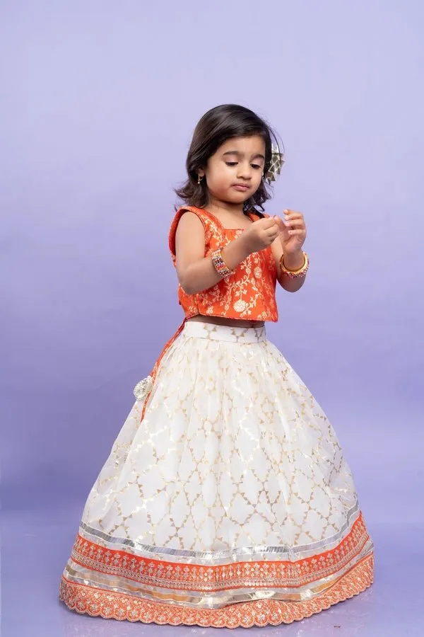 Festive orange brocade top with a golden-patterned white lehenga, perfect for celebrations